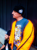 Model wearing Trap & Nap Trap House Beanie outdoors — lifestyle shot with orange jacket